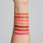 Set of lipsticks with swatches on a hand against a dark background